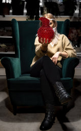 Underlay Garnet Hobnail Jug presented by a woman seated on a dark green velvet armchair